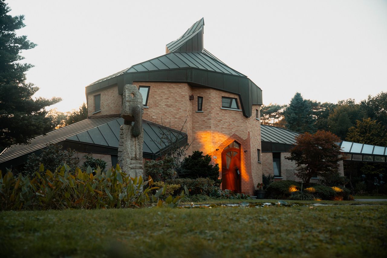 Striking modern house with artistic design and intriguing architecture, surrounded by lush greenery.